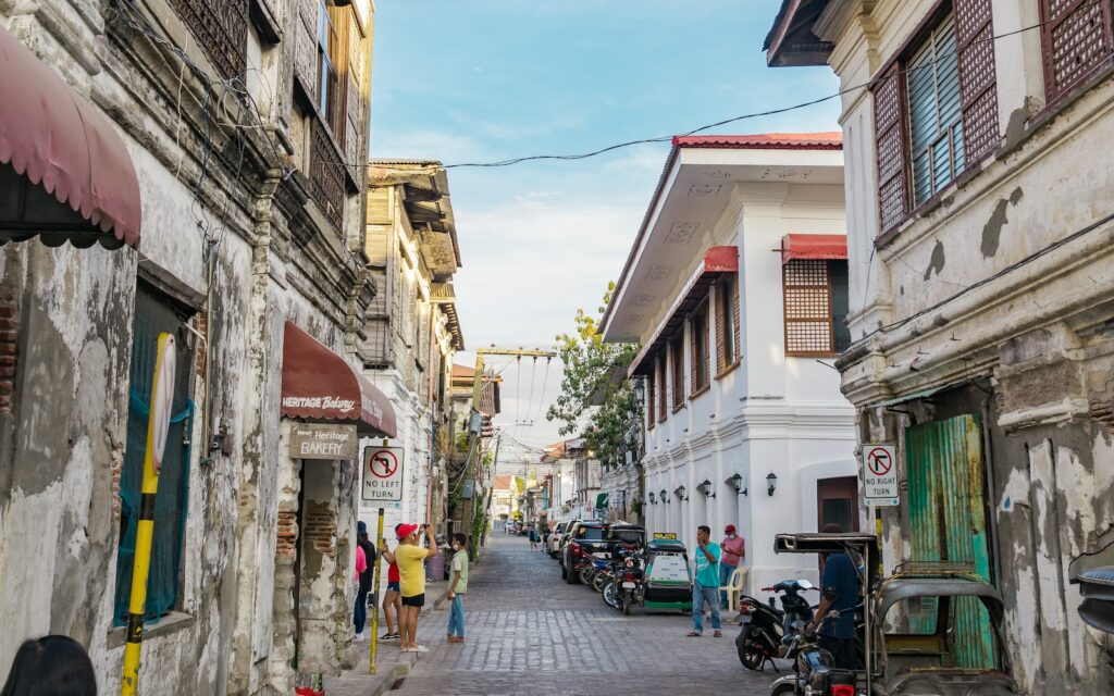 a narrow street lined with parked motorcycles and people